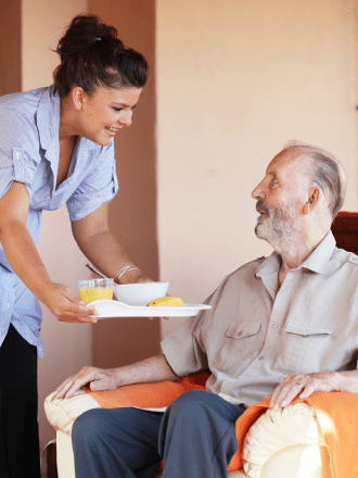 Carer Serving Food to Senior Person